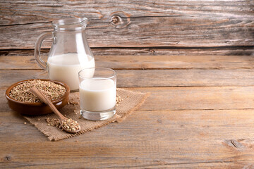 Vegan non diary buckwheat milk in glass and jug with buckwheat groats in a clay bowl on a wooden background. Vegan buckwheat drink is plant based alternative milk . Veggies healthy milk product