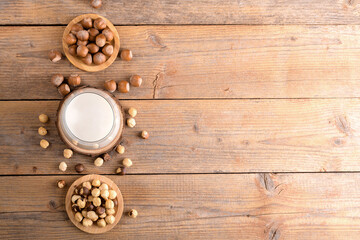 Vegan non diary hazelnut milk in glass with whole hazelnuts on a linen napkin on a rustic wooden background. Lactose free hazelnut drink is plant based alternative milk. Healthy milk product. top view