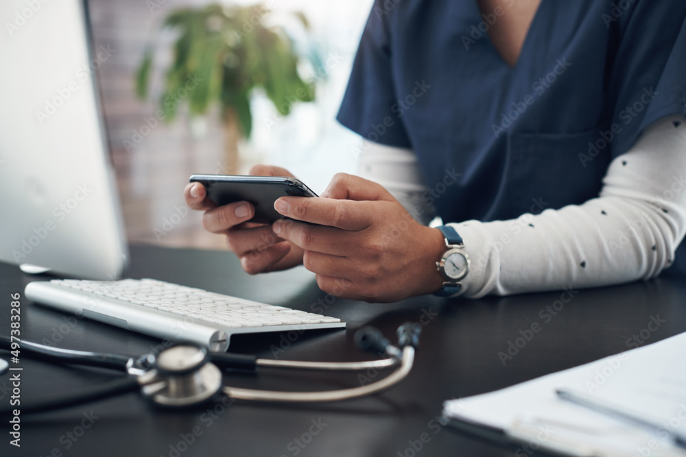 Poster watching some videos to take a break. shot of an unrecognizable doctor using a cellphone in an offic