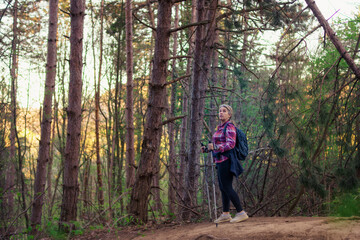 A mature woman in her 50s walks in the mountains. Use hiking poles.