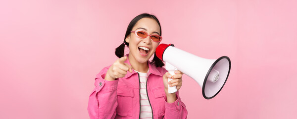 Attention, announcement concept. Enthusiastic asian girl shouting in megaphone, advertising with...