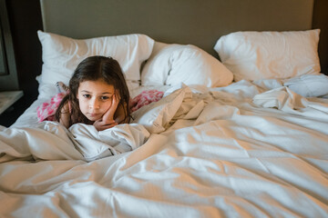 Young girl looking sad in messy bed