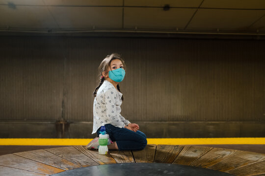 young girl waiting for subway train with mask
