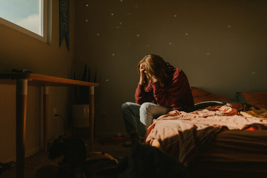 a woman with head in hands feeling anxiety and depression by window