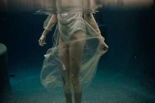 woman standing in pool wearing sparkle dress underwater