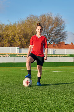 A Female Soccer Player Poses With A Soccer Ball Looking At The Camera