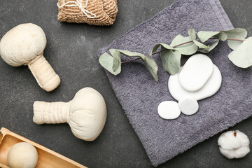 Spa composition with bathing towel, stones and herbal bags on dark background