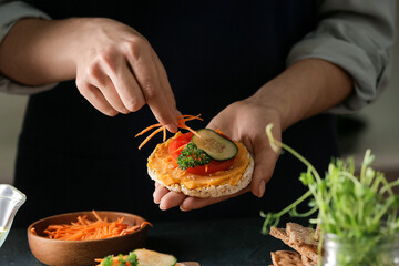 Woman making tasty sandwich with healthy hummus, closeup