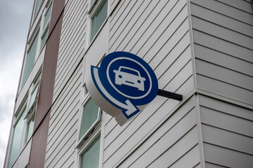 Low angle view of a blue car symbol, indicating a parking garage outside of an apartment complex
