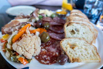 View of a bountiful selection of food on a charcuterie plate on a wooden table at a restaurant