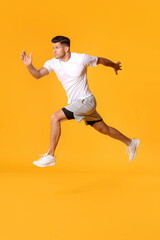 Naklejka na ściany i meble Sporty male runner on color background
