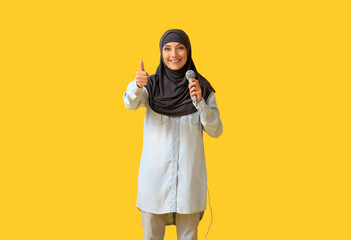 Muslim music teacher with microphone showing thumb-up on color background