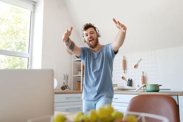Cool young man with laptop learning to dance at home