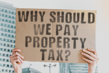 The question " Why should we pay property tax? " on a banner in men's hands with blurred background. Paying. Rate. Banking. Value. Notice. State. Revenue. Success. Wealth. Apartment. Bill. Budget