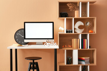 Workplace with computer and shelf unit with decor near color wall