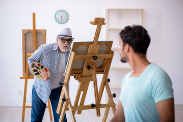 Old painter and young male model at the studio