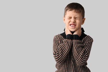 Ill little boy with sore throat on grey background