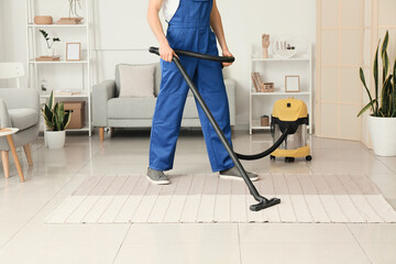 Male worker cleaning trendy carpet in room