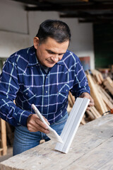 Hispanic man painting in his carpentry workshop - Latin Carpenter working with brush and paint