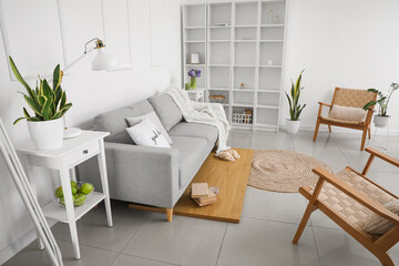Interior of light living room with sofa, tables and hyacinth flowers in vase