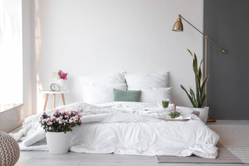 Interior of stylish room with beautiful flowers and breakfast on bed