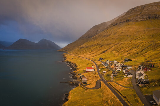Faroe Islands, Kalsoy island, Husar village in sunset light durig twilight with pink sky and cliffs. November 2021