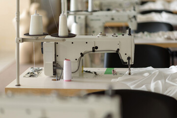 Professional sewing machine in the production workshop. Workplace of a seamstress or dressmaker. Manufacture and tailoring. Clothing industry. Textile factory. Manufacture of wedding dresses.
