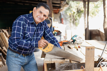 Hispanic man working with saw in his carpentry workshop-Latin Carpenter working