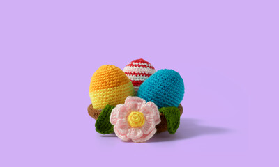 Happy Easter design. Nest with eggs and daisies made in crochet and colored wool. Violet background