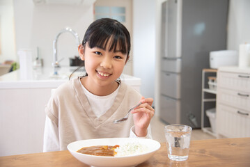 Obraz na płótnie Canvas 1人でカレーライスを食べるアジア人の子供