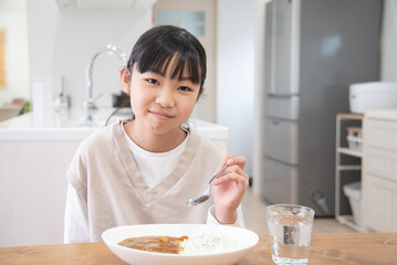 Obraz na płótnie Canvas 1人でカレーライスを食べる小学生の女子