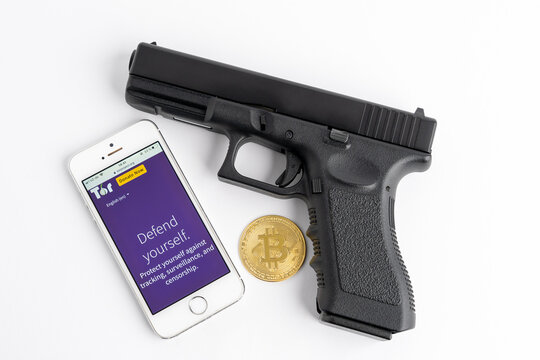 DRESDEN, GERMANY - 19. March 2021: Tor browser on a smartphone, a pistol and a Bitcoin as symbols for the darknet. Using BTC money in the dark web to buy illegal things like a weapon.