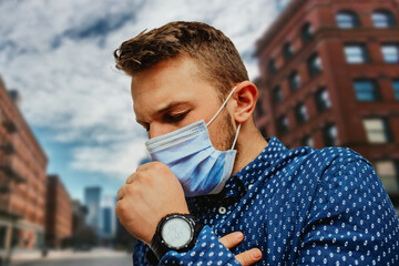 A photo of a businessman in a shirt coughing in the city center while wearing a protective mask on...