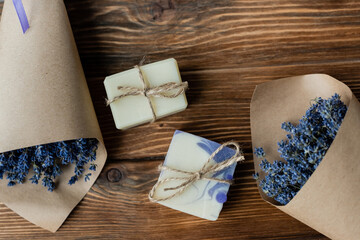 Top view of handmade soap near bouquets of lavender on wooden surface.