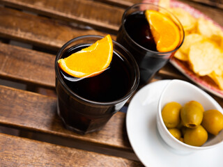 Traditional spanish appetizer, red vermouth garnished with wedge of orange, olives and potato chips