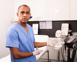 Obraz premium Professional experienced Hispanic male beautician welcoming in clinic of modern aesthetic medicine, telling about cosmetology treatments