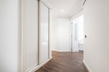 Fototapeta premium hallway hall with built-in wardrobe with white wooden sliding doors and dark parquet floor