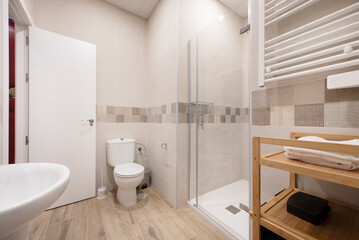 Fototapeta na wymiar Bathroom with white porcelain sink, square shower stall with glass door, heated towel rail and bamboo wood shelf