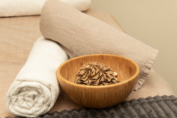 Fototapeta na wymiar Varnished bamboo wood bowl and rolled towels on massage table