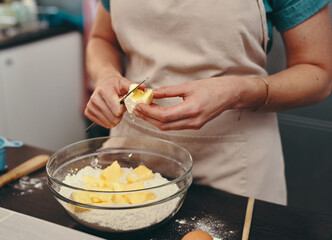 Baking is not just a hobby, its a passion. Cropped shot of an unrecognizable woman cutting blocks of butter while baking inside her kitchen at home.