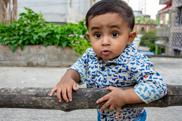 An infant child is standing and holding a dried bamboo and looking at the camera. Baby's smiley...