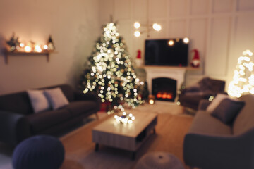 Blurred view of room with beautiful Christmas tree near fireplace
