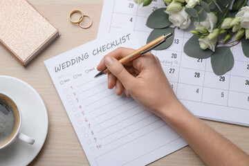 Woman filling Wedding Checklist at wooden table, top view
