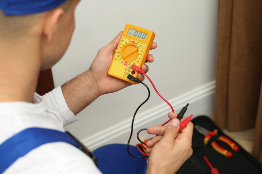 Professional electrician with voltage tester indoors, closeup