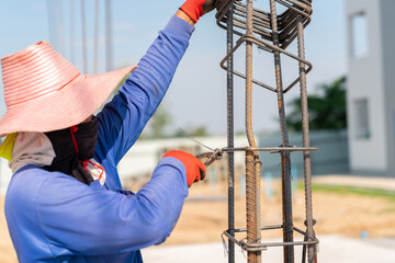 Workers use pliers to tie wires to rebar to pour concrete columns