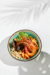 Seafood salad in asian style on white background with hard shadow. Salad with shrimps, mussels, soy bean sprouts. Asian shrimp food. Healthy menu - prawns or shrimp and mussels. Top view seafood.