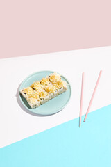 Cheese maki roll on blue ceramic plate. Sushi roll in Caesar style on coloured backdrop. Sushi menu concept. Modern japanesse food. Maki sushi with cheese in minimal style