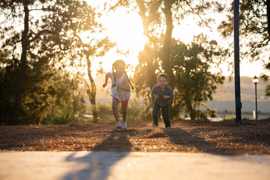 Ni&ntilde;os felices amigos hermanos jugando corriendo brincando saltando disfrutando de un atardecer en un parque al aire libre
