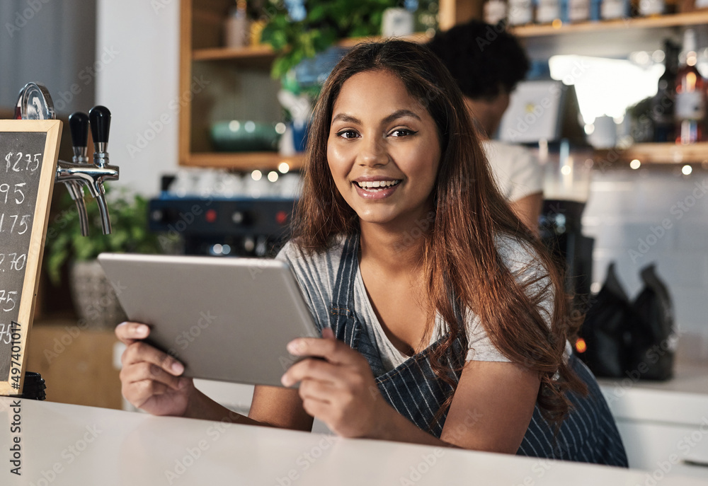 Aufkleber Technology is an integral part of how restaurants operate. Portrait of a young woman using a digital tablet while working in a cafe.
