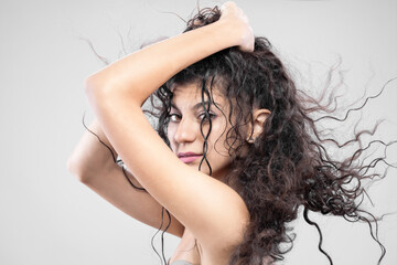 Fototapeta premium Beautiful brunette girl with long wet hair, studio portrait. Serious face expression